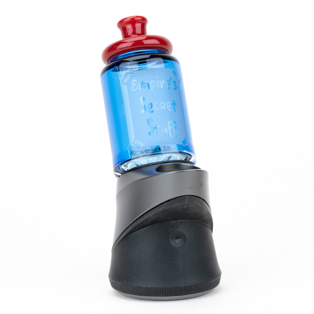 Empire Glasswork's Secret Stuff Bottle Top for the Puffco Peak Pro. Secret Stuff bottle is made of blue glass body with a red, glass top. Written on the bottle is "Empire's Secret Stuff".