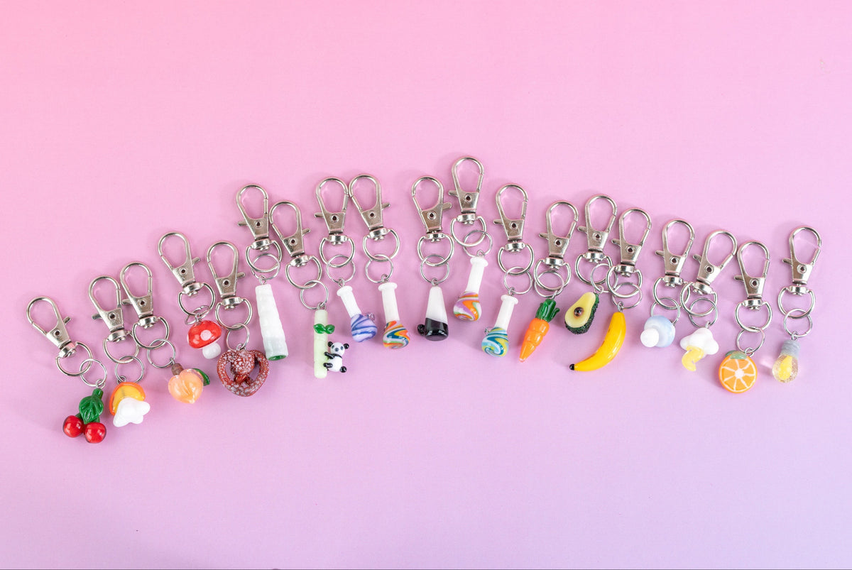 Collection of Puffco charms on pink background
