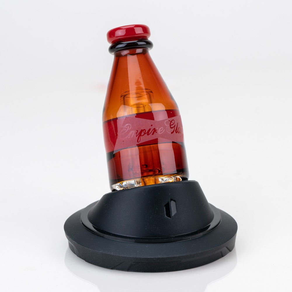 American Lager Puffco Peak pro glass attachment with amber beer bottle design seated on an Empire Glassworks Peak display stand