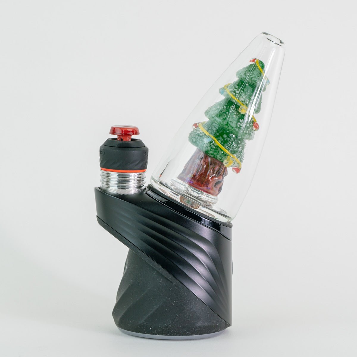 A Christmas tree shaped glass attachment sitting on a Puffco Peak Pro Device by Empire Glassworks