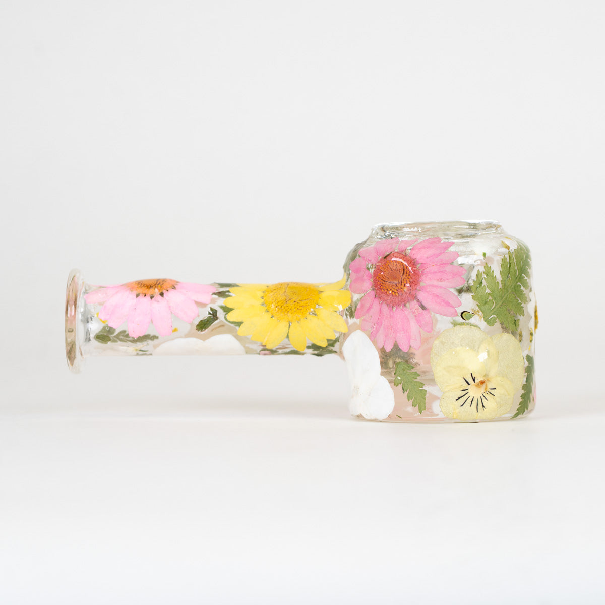 Spoon pipe with hand pressed pink, yellow, and white flowers on a plain white background