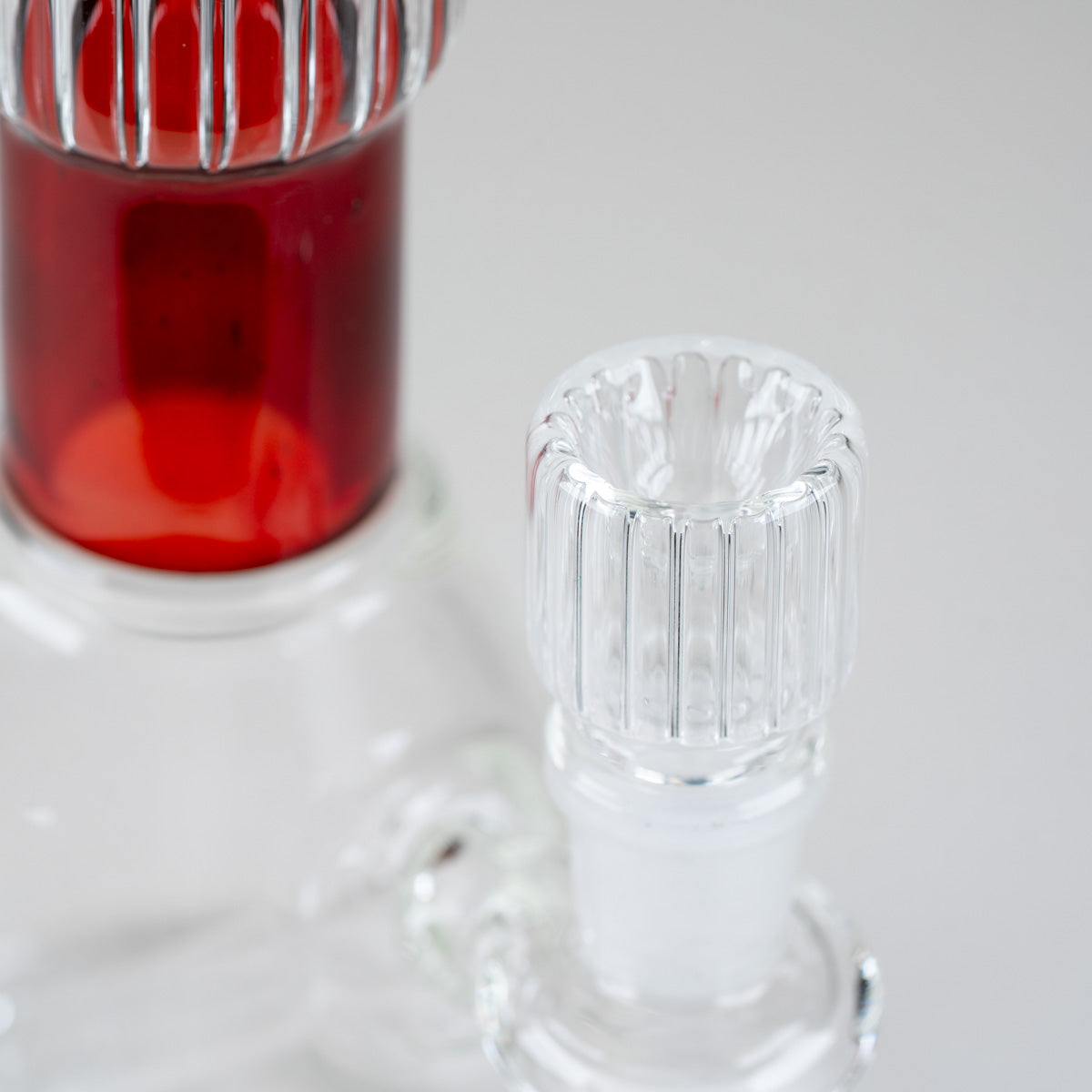 Close-up of the Ruby Signature Beaker's architectural ribbed glass neck and sculpted red comfort rim