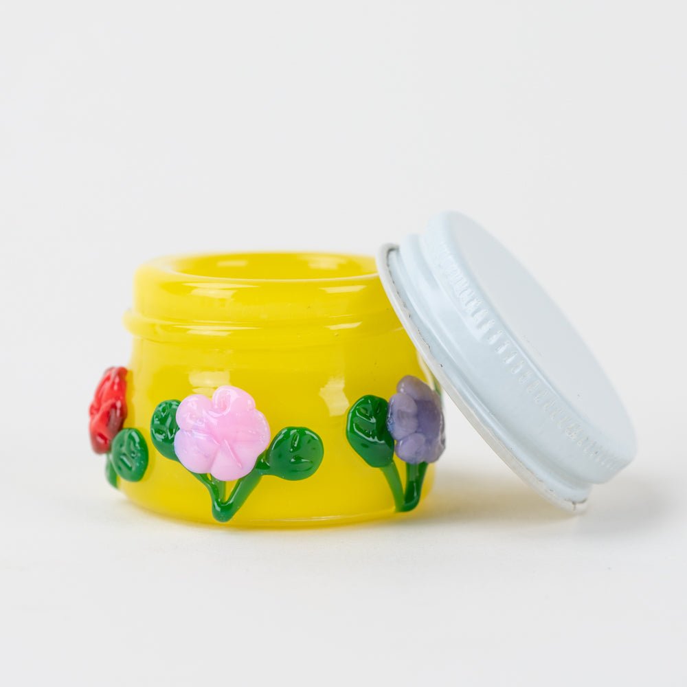 Yellow glass concentrate jar with red, pink, and purple flower artwork