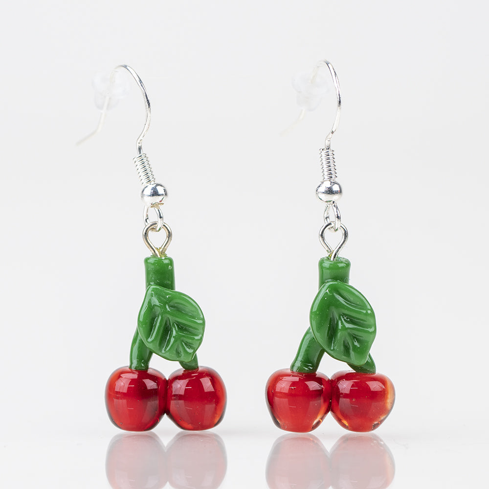 A set of two dangle earrings each featuring to cherries with their stem. The cherries are a deep cherry red and the stem is green. The hoop of the earrings is a silver. Cherry Glass Dangle Earrings - Set of Two Empire Smokes