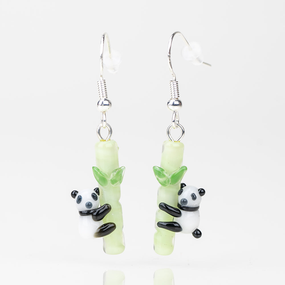 Two adorable earrings featuring a panda hugging a bamboo log. Each earring is made of glass and has a sterling silver hook to loop into your ear. The Bamboo portion of the earring is a light green and the bamboos are black and white.
