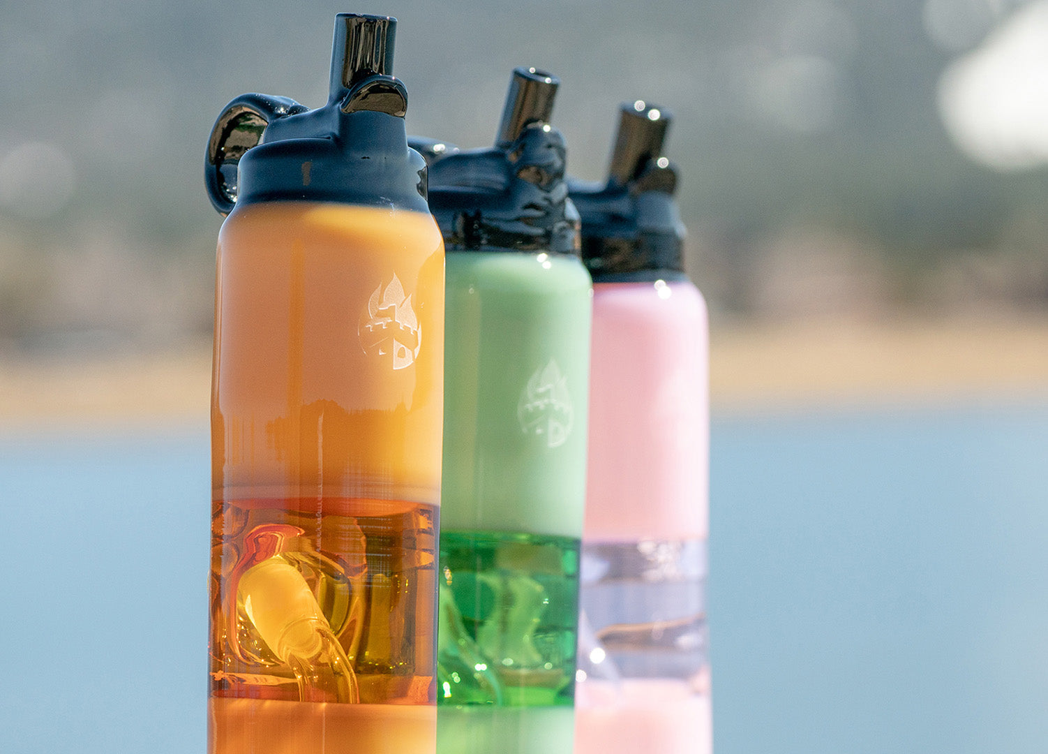Three colorful glass water bottles with ocean background