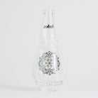 Clear glass bottle with floral design and text on white background