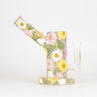 A clear glass water pipe with a floral design featuring pressed-style pink, white, and yellow flowers with green leaves, set against a plain white background.