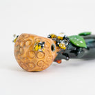 A closeup of glass pipe with bee and honeycomb design on white background