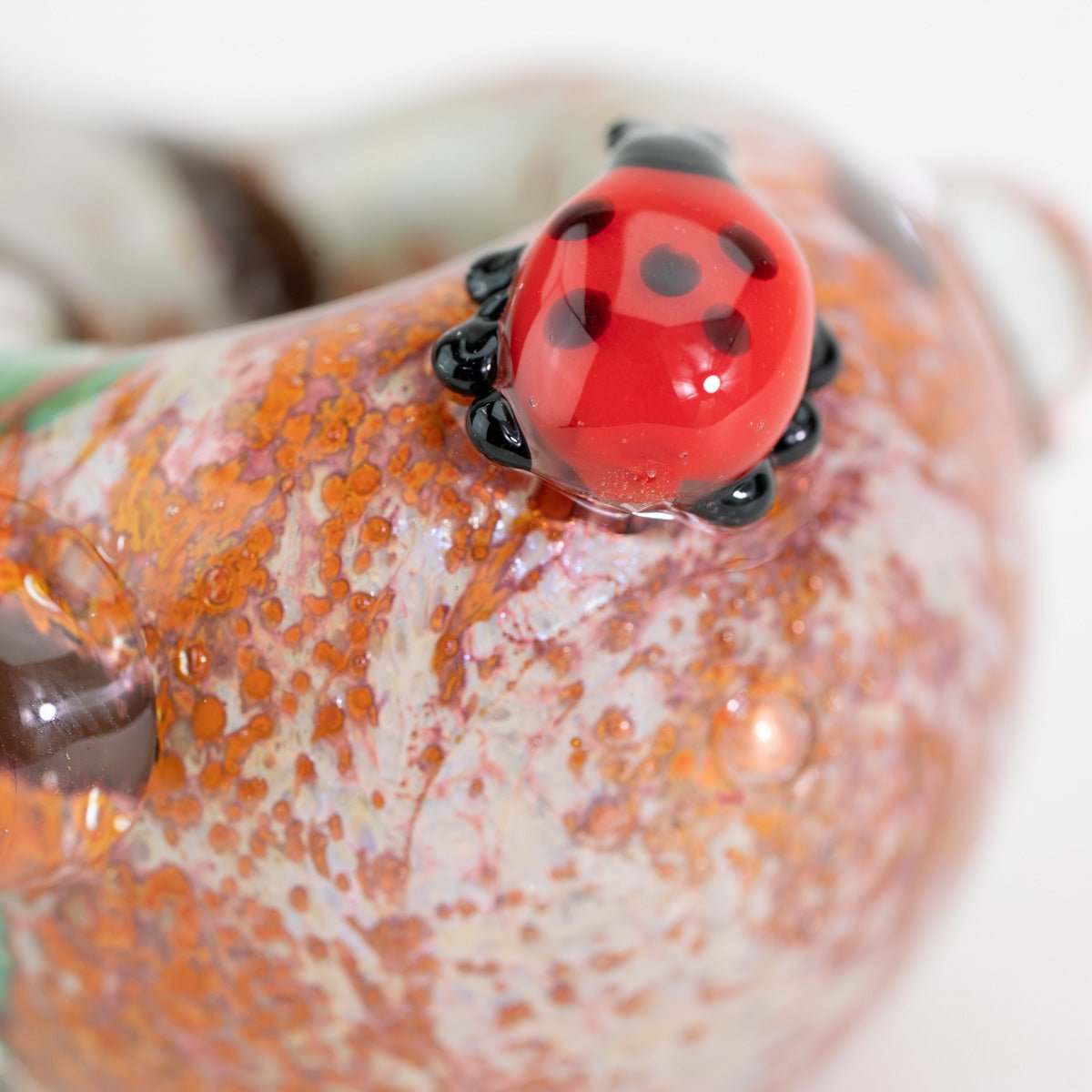 A closeup of glass lady bug on small spoon pipe