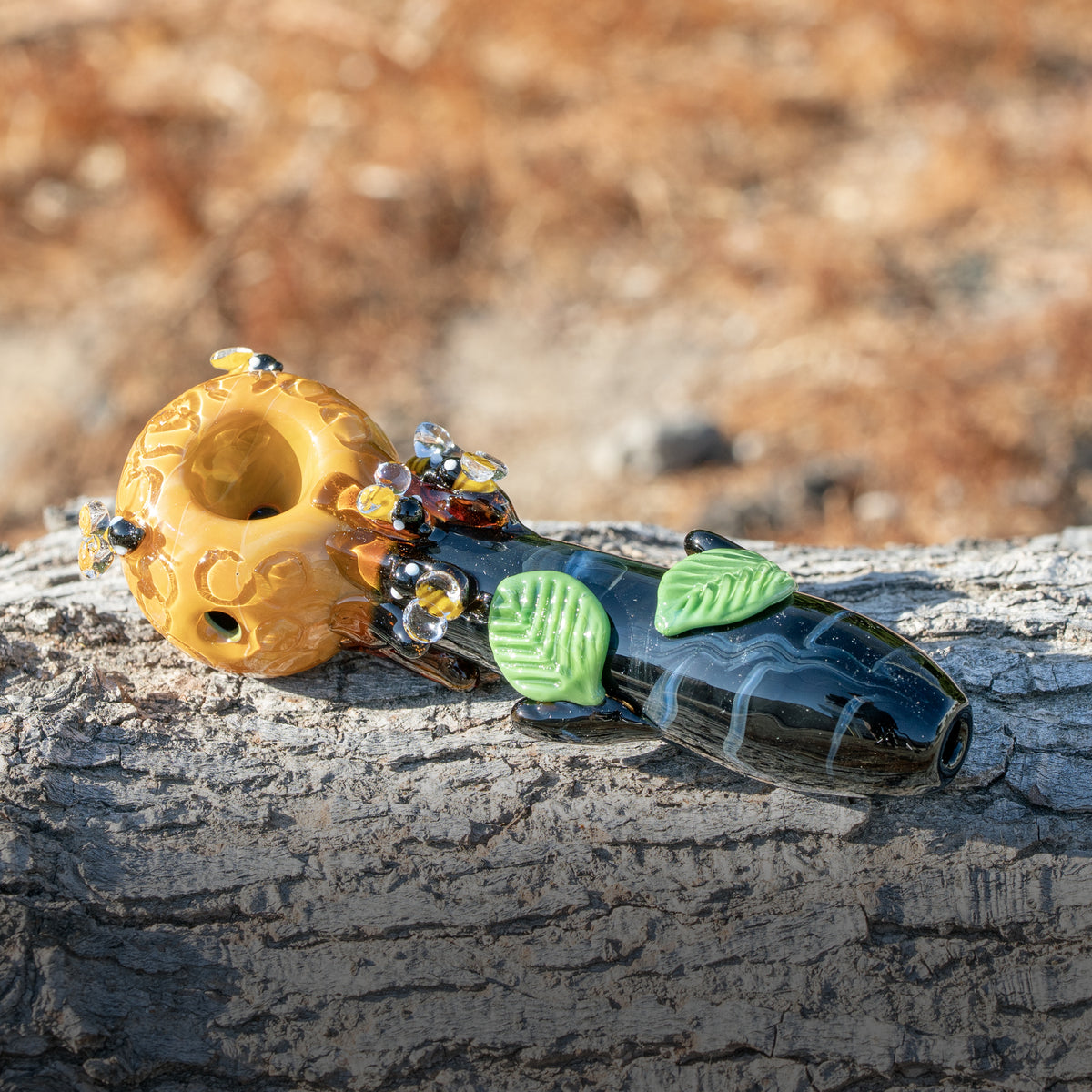 A bee-themed spoon pipe made of glass and designed by Empire Glassworks
