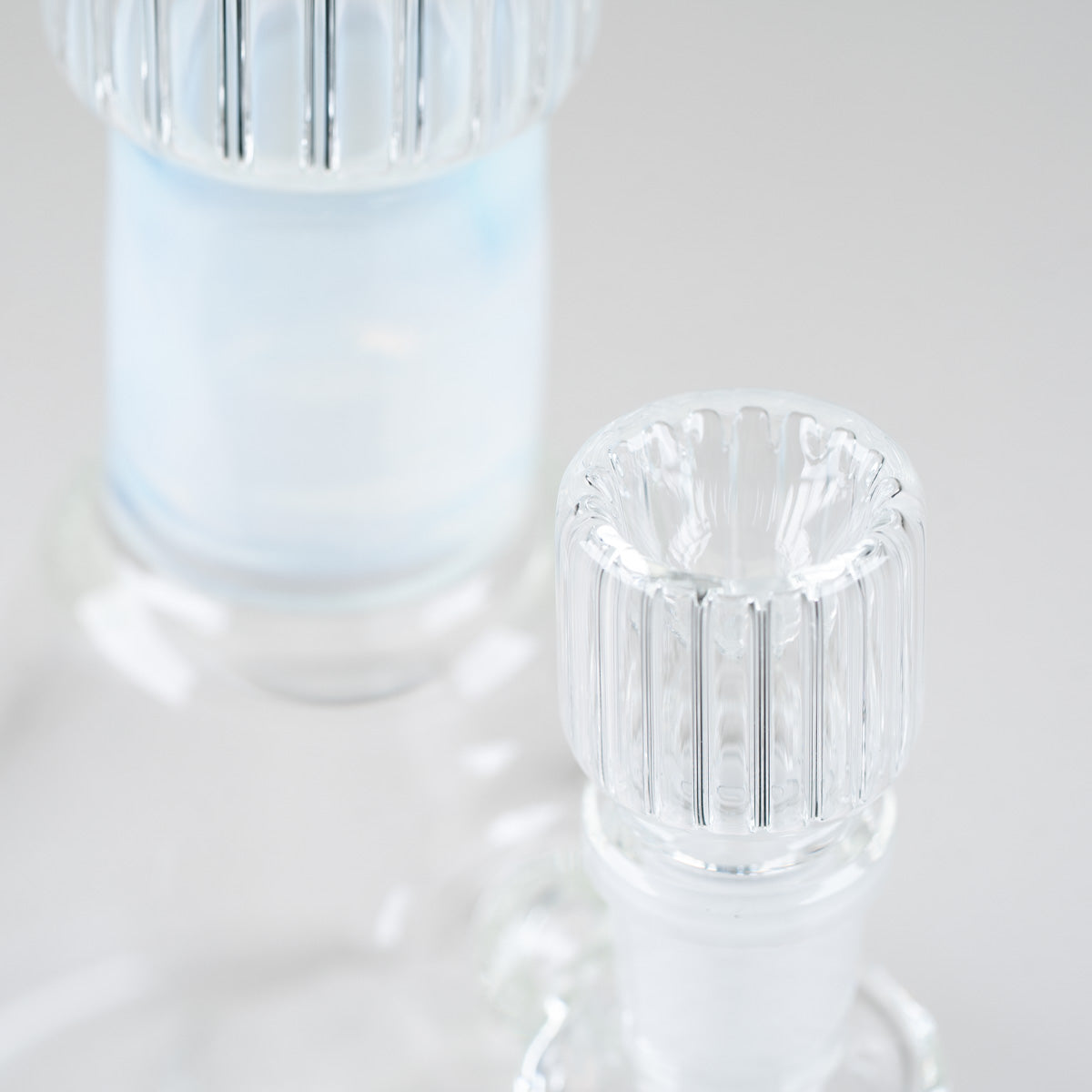 Detailed view of the clear ribbed glass bowl beside the soft blue neck accent on the Empire Glassworks Celeste Beaker