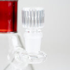 Angled close-up of the clear ribbed glass bowl with the Ruby Signature Beaker's red neck accent in the background