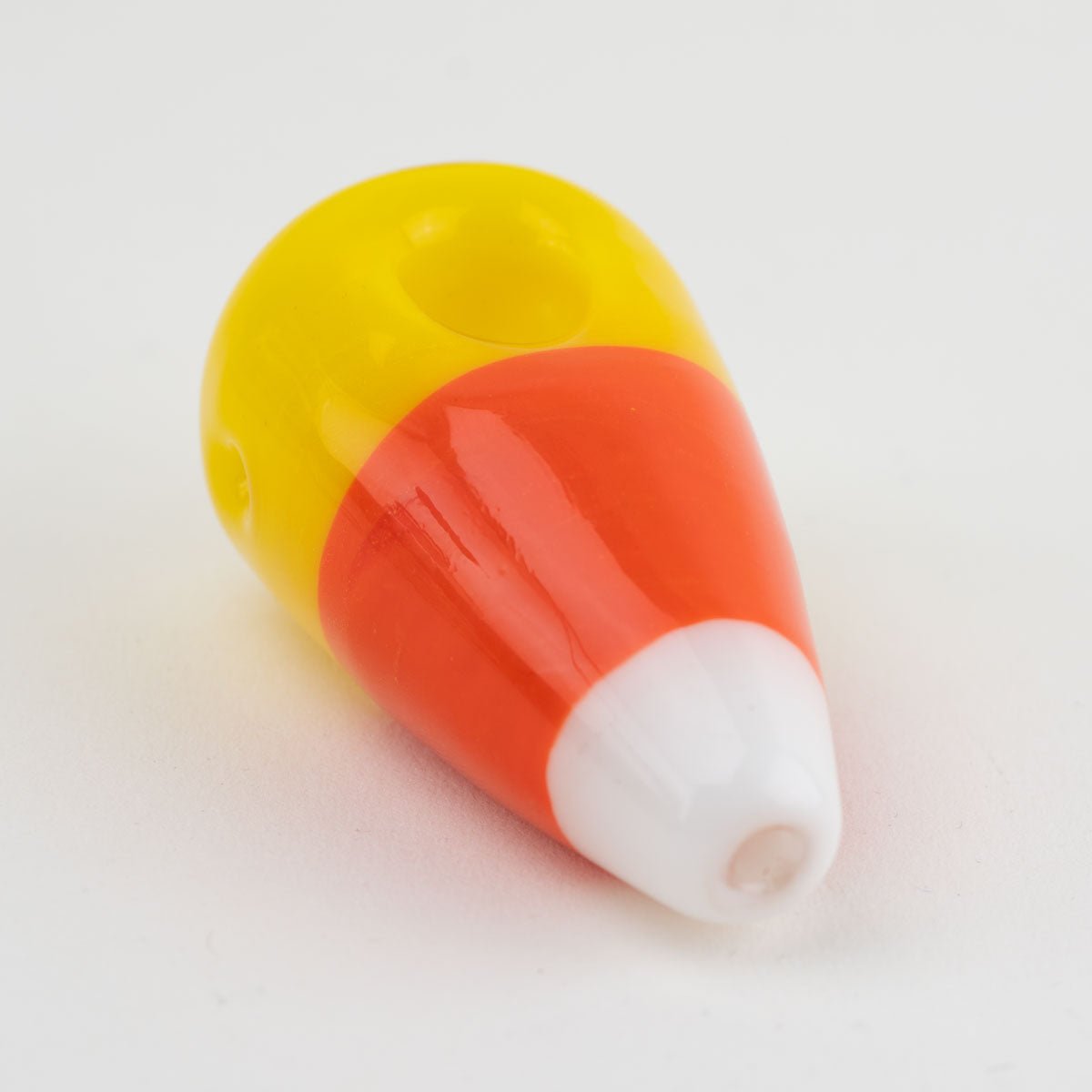 Candy corn-shaped spoon pipe on a white background