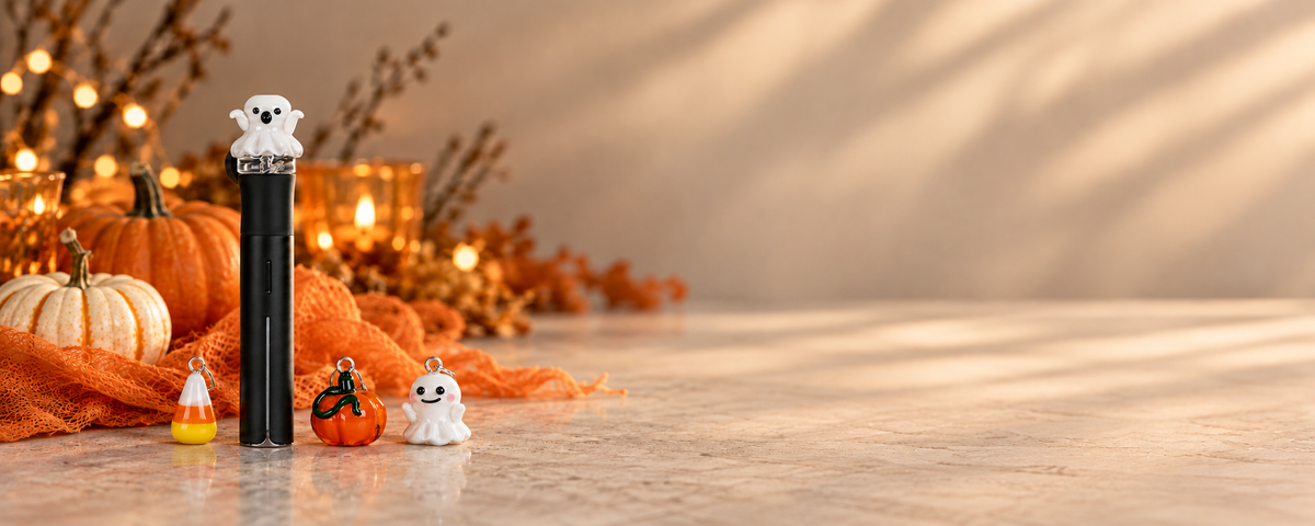 Halloween glass charms and a ghost-topped black device styled with pumpkins and warm fall decor on the Empire Smokes homepage banner