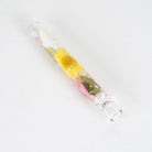 A clear glass tube with a glass bottom, containing a preserved yellow sunflower and pink flowers in clear resin, photographed on a white background.