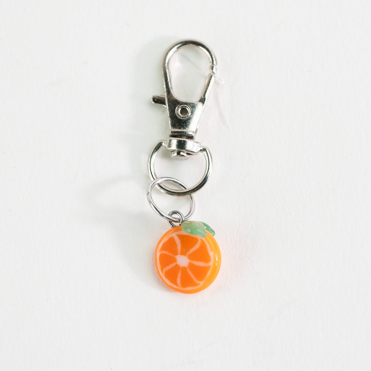 Close-up of the Mmmelty orange glass charm with colorful citrus detail