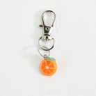 Close-up of the Mmmelty orange glass charm with colorful citrus detail