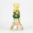 A clear glass beaker with decorative glass pieces and pressed flowers