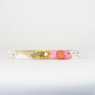 A clear glass chillum with decorative pressed flowers on a white background