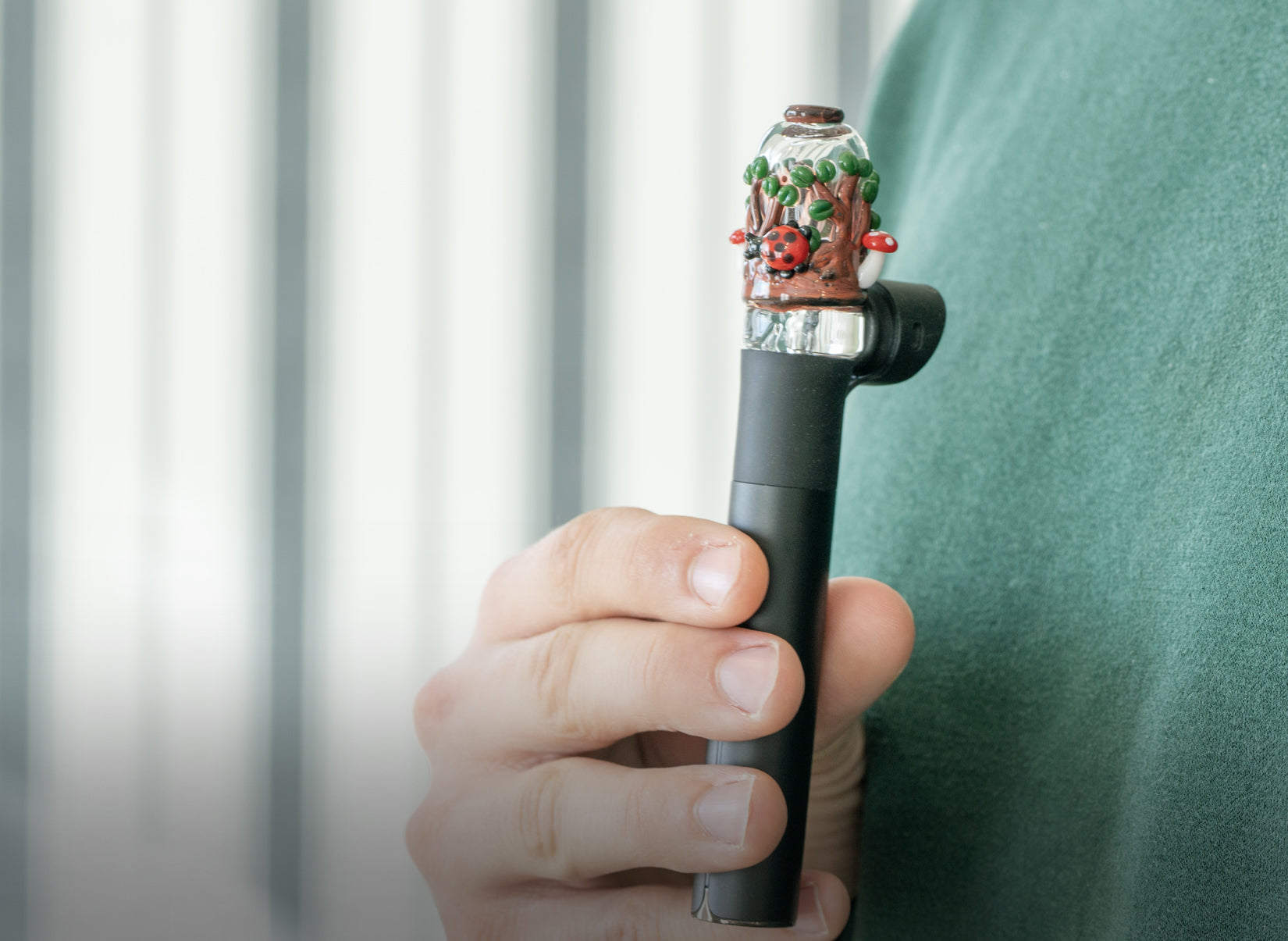 A glass attachment for the Puffco Peak Pivot held infront of a green background