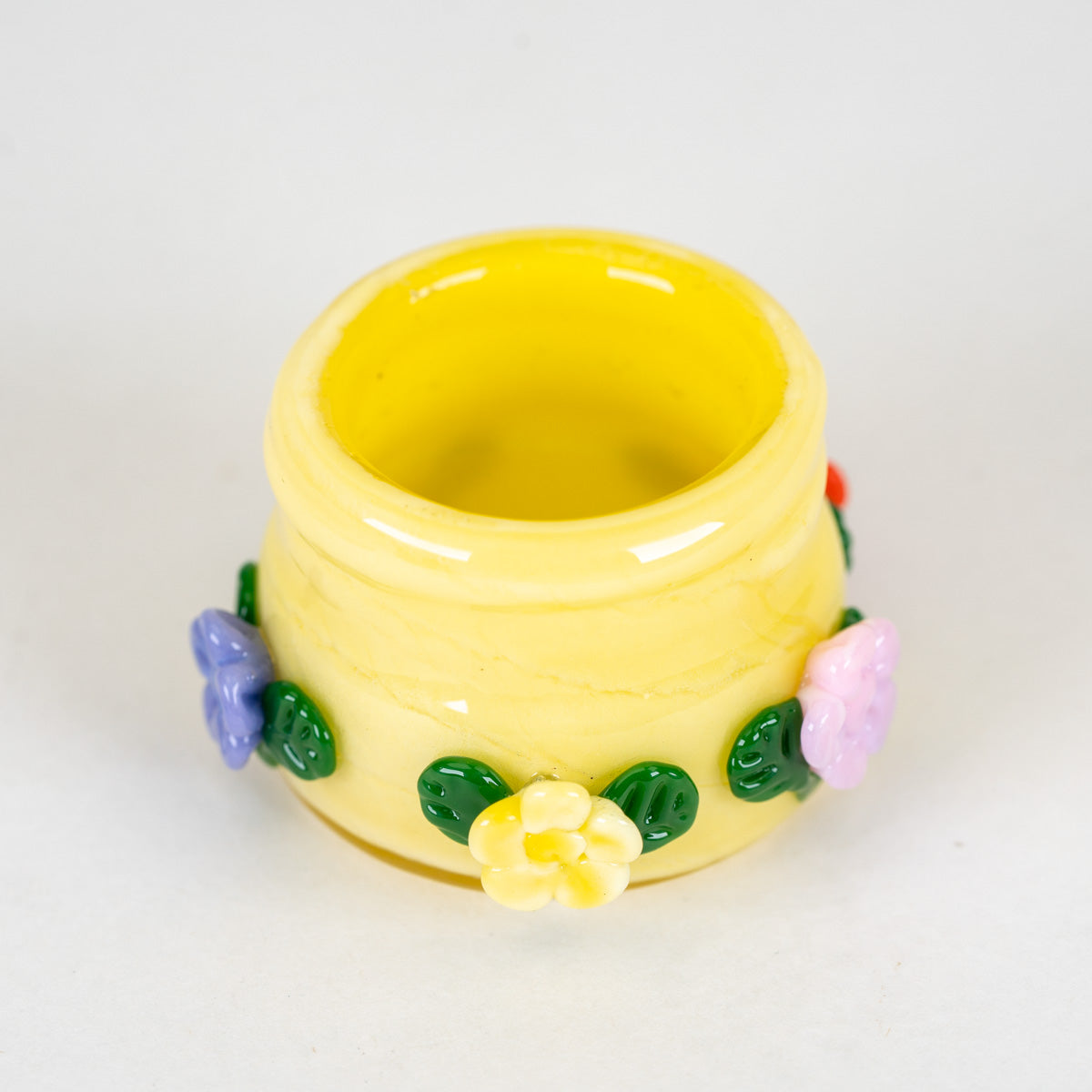 A small glass terp jar with open top with colorful flowers and decorations